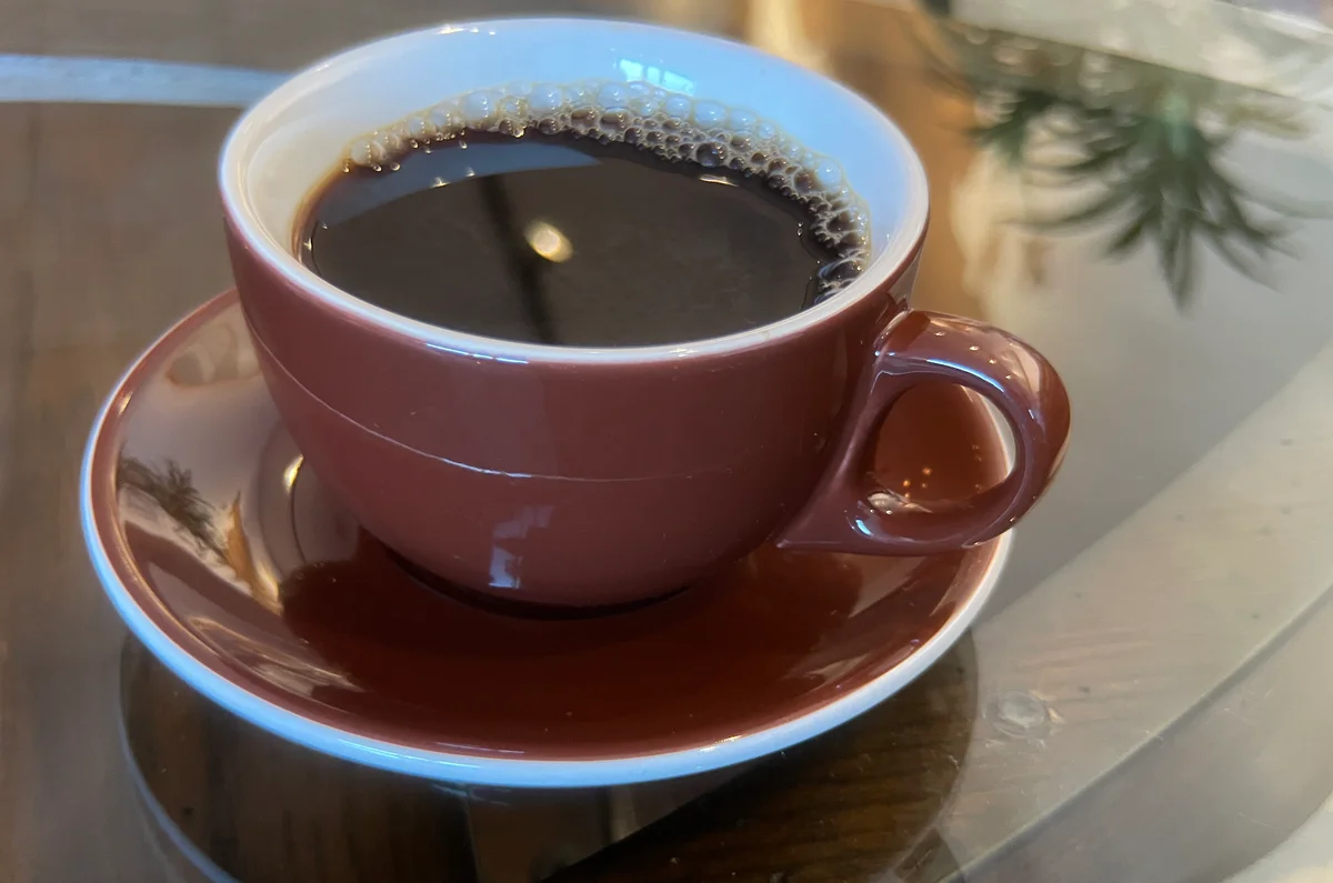 Drip coffee in a brown ceramic cup on a glass table